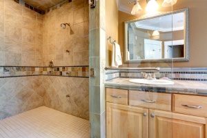 completed bathroom remodel in Fairfax, VA equipped with a glass shower and nice wood cabinets