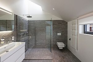 a glass shower that includes a vertical shower head to provide extra luxuries