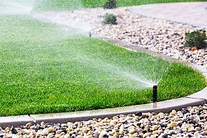 a sprinkler system watering a yard that the homeowners have found several uses for topsoil for including fixing damage in the lawn