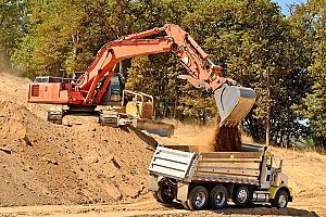 an excavator loading up a dirt carrier for any online fill dirt ordering needs around the area of Maryland by homeowners and business owners