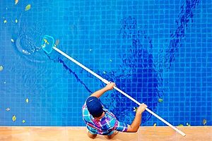 a man using a net to clean an unused pool and is therefore wasting time and money versus choosing pool removal services