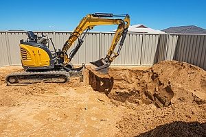 an excavator digging out Virginia fill dirt in a backyard that is going to have an inground pool installed into it