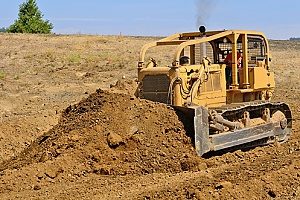a bulldozer scooping up clean fill dirt before loading it into a dirt carrier for transportation