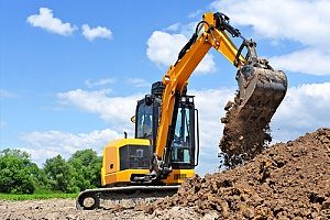 an excavator digging up fill dirt for a commercial project that requires excavation and land grading