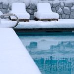 an inground swimming pool surrounded by snow that must be drained in order to receive Fairfax, VA pool removal services