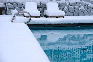 an inground swimming pool surrounded by snow that must be drained in order to receive Fairfax, VA pool removal services
