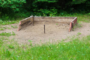 a horseshoe pit built in a sandbox area in a backyard