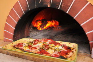 a pizza on a colorful plate that was baked in an outdoor pizza oven