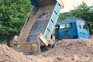 screened fill dirt being poured onto land by a dump truck