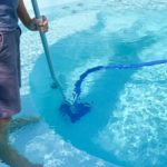 a man cleaning a pool with swimming pool problems