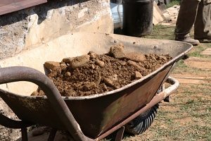 dirt in a wheelbarrow around a foundation