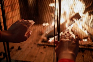 a man warming his hands at an outdoor fireplace