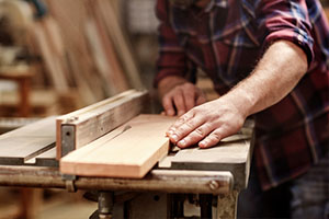 hands of a craftsman cutting a wooden plank