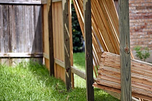 Lumber leaning up against fence posts 