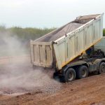 construction materials being transported through dump truck hauling services