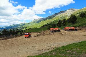 Orange Dump trucks leveling the slope by filling dirt