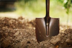 A shovel and soil. Soil acidity refers to how acidic or alkaline the soil is in your lawn and garden