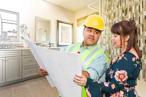 A bathroom remodeling contractor talking with female client over blueprint plans