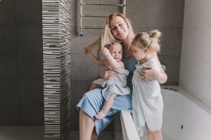 A happy mother with two of her little daughters in the bathroom. Remodeling cost of bathroom can be expensive