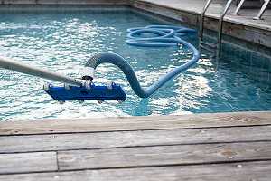 Cleaning backyard inground swimming pool with vacuum tube cleaner