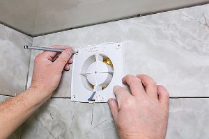 Worker installing half bathroom wall ventilation