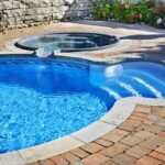 outdoor in ground residential swimming pool in backyard with hot tub