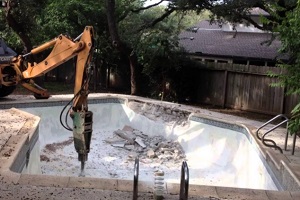 jcb with stone crusher demolishing swimming pool