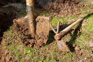 garden shovel and hoe with soil in selective focus