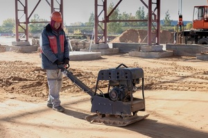 worker compacts the soil with a vibrating rammer on a construction site