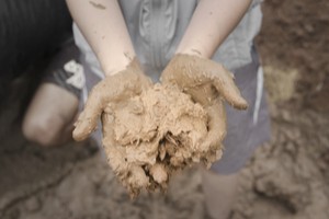 A boy showing his hands that has wet clay soil
