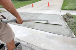 A man surfacing a concrete driveway with a finishing trowel