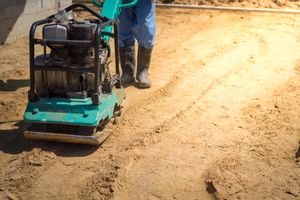 Man compacting soil with the use of a soil compactor