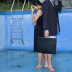 A man and a woman are standing inside an empty pool and looking tense