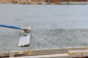 Man forming concrete on the driveway with a concrete trowel