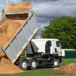 A dump truck off-loading sand in a ground
