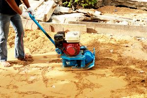 A man doing dirt compaction with a vibratory compactor tool