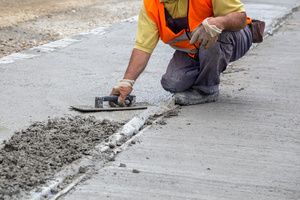A mason applying sealer on a concrete road