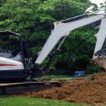 An excavator machine is moving the clean fill dirt away from the yard