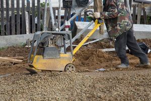 A man compacting dirt with a hand soil compactor machine