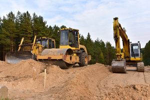 Soil compactor, excavator, and dozer working on a slope