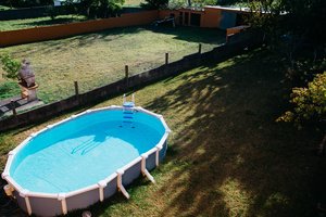 An above ground pool at the corner of the yard