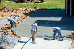 Three workers leveling a concrete driveway