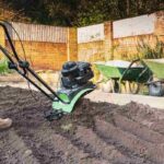 hand held mechanical rotavator being used to reshape a garden after old turf has been removed