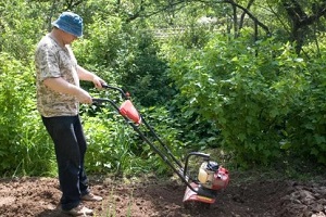 man in garden with cultivator